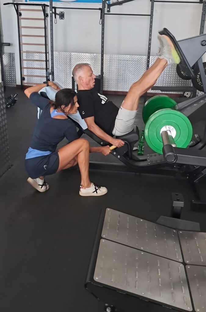 Una trainer segue una persona che si allena su un attrezzo in palestra